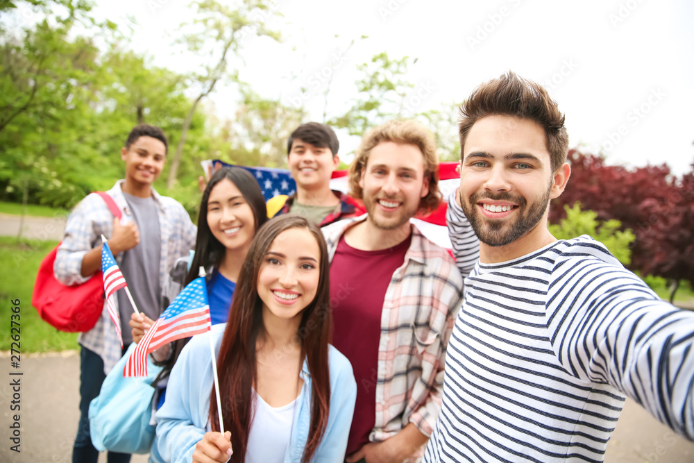 Obraz premium Group of students with USA flag taking selfie outdoors