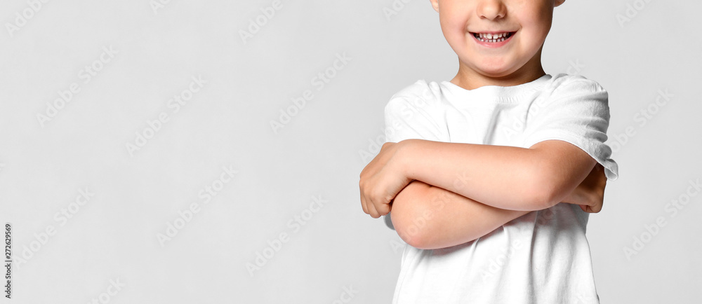 Beautiful little boy child in a white t-shirt, holding his arms crossed and smiling, standing on a white background Beautiful little boy child in a white t-shirt, holding his arms crossed and smiling, standing on a white background