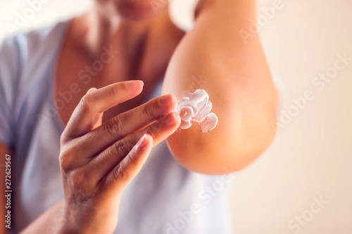 Woman applies cream on dry elbow.People, healthcare and medicine concept