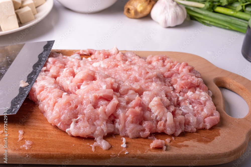 Minced meat and traditional Chinese knife Tsai Dao on a cutting board and ingredients for cooking Mapo doufu. Minced meat and traditional Chinese knife Tsai Dao on a cutting board and ingredients for cooking Mapo doufu.