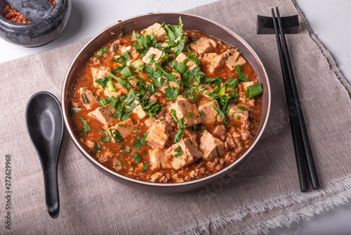 Traditional Chinese dish Mapo tofu with minced meat and tofu cheese in a bowl on a linen rustic napkin
