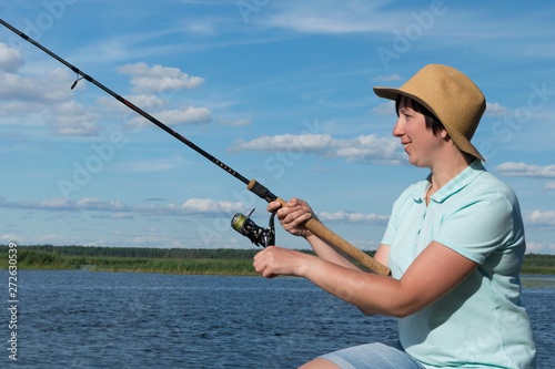 girl with a hat is fishing on a river on a sunny day, close-up