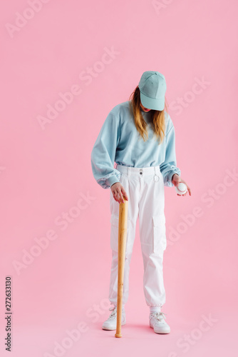 Photography full length view of teenage girl in cap holding baseball bat and ball isolated o