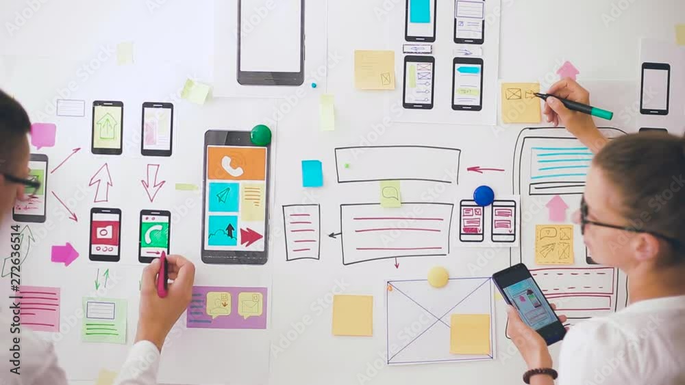 Designers is developing a web application for mobile phones. Woman draws a mockup of interface to smartphone. User experience. 