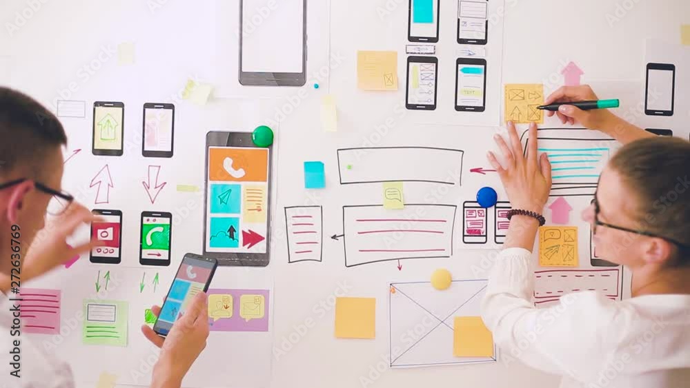 Designers is developing a web application for mobile phones. Woman draws a mockup of interface to smartphone. User experience. 