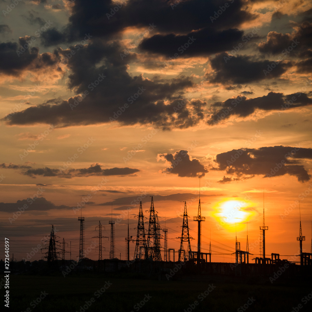 Sunset before a thunderstorm.Panorama. Electric power industry and nature concept.Power lines and sky with clouds.Wires over the fields.Field and aerial lines, silhouettes at dusk.