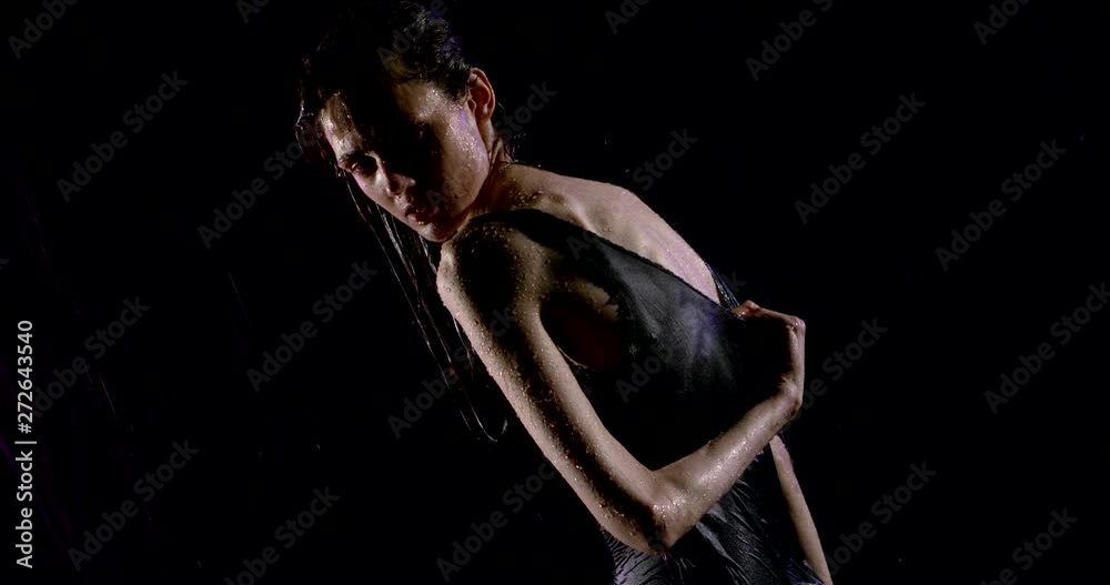 anorexic woman is posing in darkness under water stream, wriggling her body, looking at camera anorexic woman is posing in darkness under water stream, wriggling her body, looking at camera