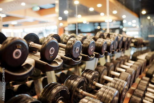 Rows of metal dumbbells on rack for strength training in gym