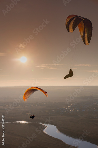 Paraglide with a paraglider in a cocoon against the background of fields of the sky and clouds. Paragliding Sports