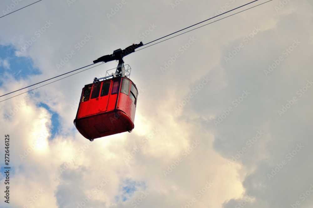 ropeway and funicular road in mountain, red cabin against a background of blue cloudy sky ropeway and funicular road in mountain, red cabin against a background of blue cloudy sky