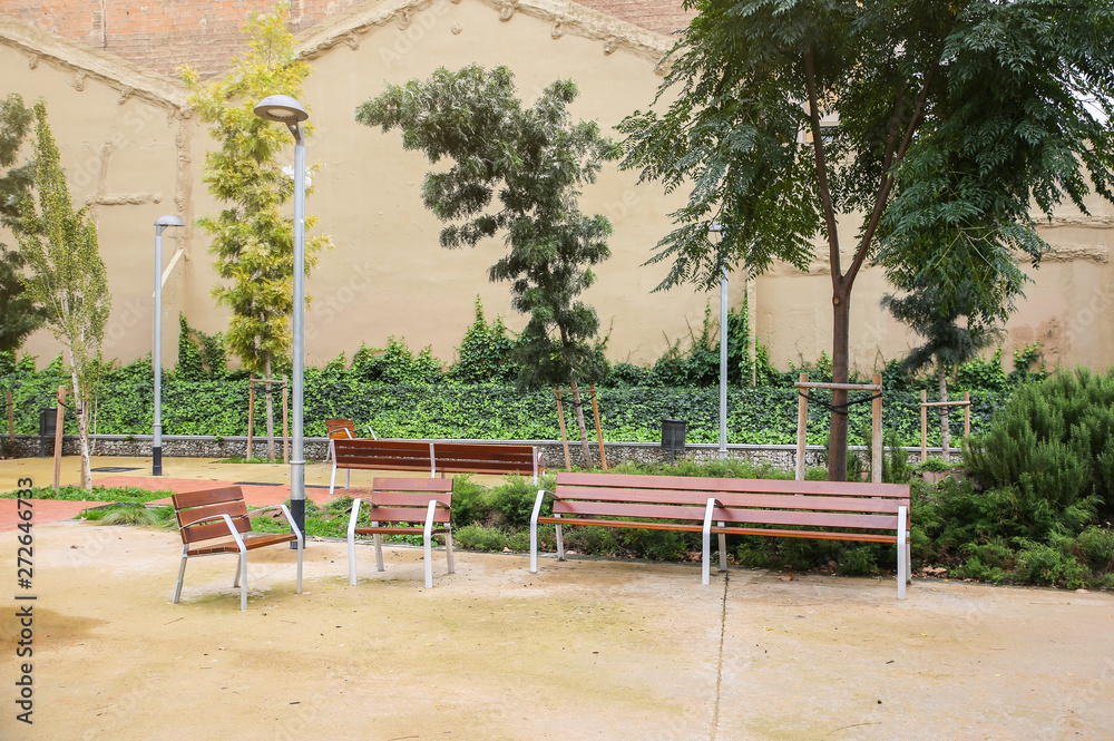 Modern park in Barcelona. Nice square with benches and trees. Time to have a rest. Urban amenities.