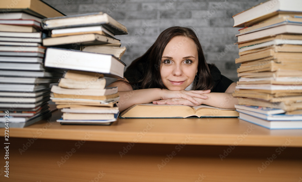 Beautiful woman student studying with a lot of paper books on the table Beautiful woman student studying with a lot of paper books on the table