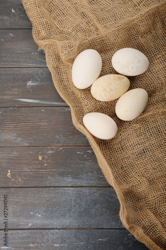 Goose eggs located on burlap on wooden dyed background. Top view.