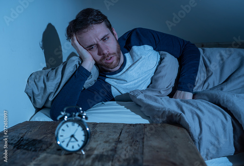 Принти на полотні Desperate stressed young man whit insomnia lying in bed staring at alarm clock t