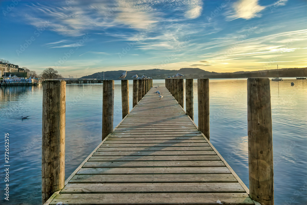 A jetty on a calm Windermere at sunset.
