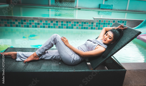 Beautiful Asian woman relaxing on folder chiar and enjoy fresh air beside swimming pool ool photo