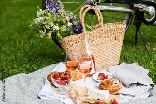 Fototapeta Naklejka Na Ścianę i Meble -  Beautiful summer picnic with strawberries, cheese and rose wine on the lawn in the city park