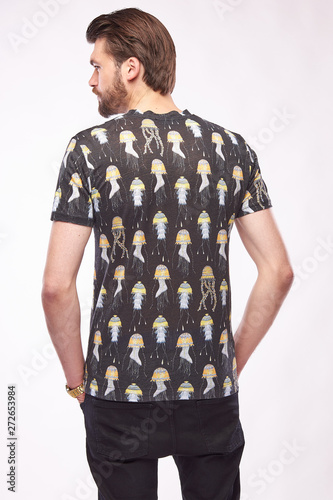 Wallpaper Mural Fashion portrait of young male model with dark hair and beard, posing in grey t-shirt with print and black pants. White background Torontodigital.ca