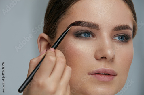 Eyebrow coloring. Woman applying brow tint with makeup brush photo