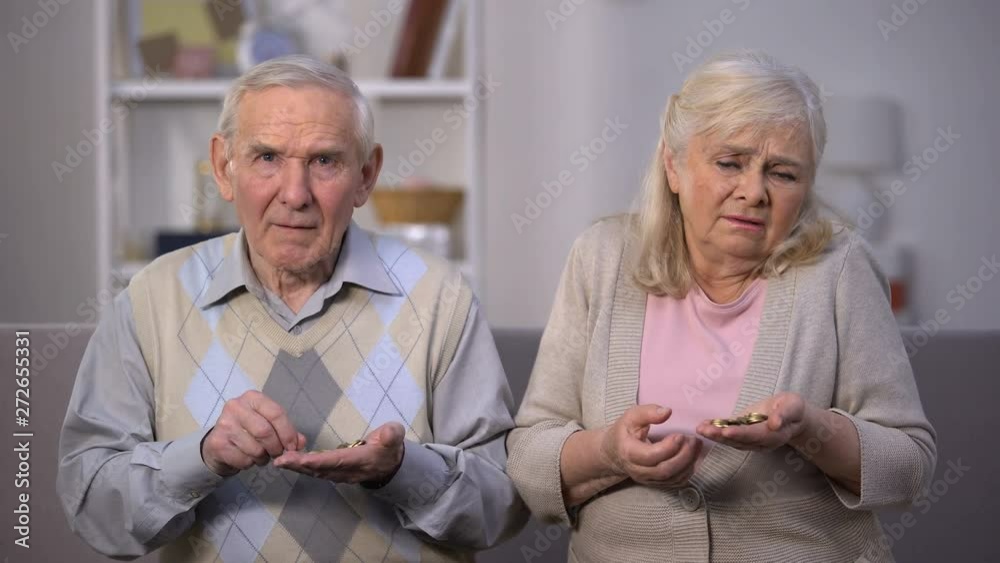 Depressed old couple counting coins in open palm, no money for living, poverty Depressed old couple counting coins in open palm, no money for living, poverty