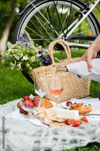Fototapeta Naklejka Na Ścianę i Meble -  Man's hand pouring rose wine into glasses, summer picnic