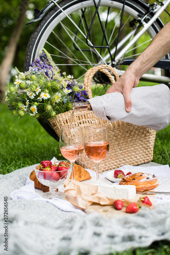 Fototapeta Naklejka Na Ścianę i Meble -  Man's hand pouring rose wine into glasses, summer picnic
