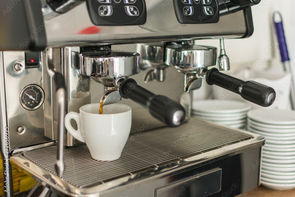 Espresso pouring from coffee machine into one cup Espresso pouring from coffee machine into one cup