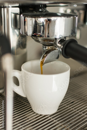 Espresso pouring from coffee machine into one cup