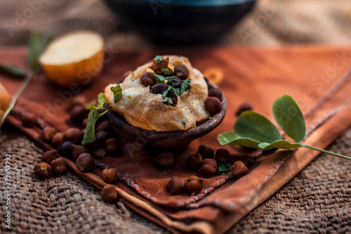 Famous Indian & Asian street food dish i.e. Golgappa snack in a clay bowl along with its flavored spicy water in another clay vessel. Horizontal shot of the snack and its ingredients present. photo