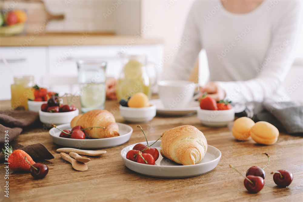 Croissant and variety of berries for breakfast on wooden kitchen table. Modern Kitchen Interior Croissant and variety of berries for breakfast on wooden kitchen table. Modern Kitchen Interior