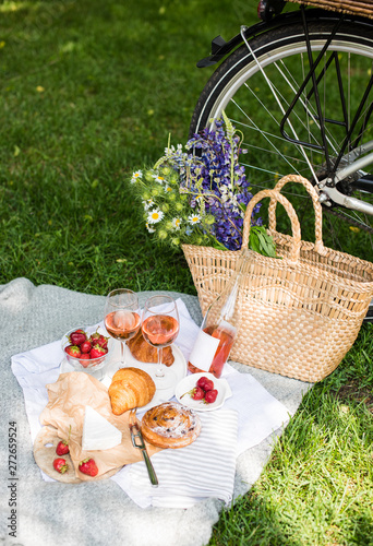 Beautiful summer picnic with strawberries  cheese and rose wine on the lawn in the city park