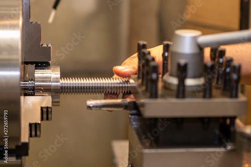The lathe machine cutting the thread on the steel shaft.The turning machine making the thread on the steel shaft.