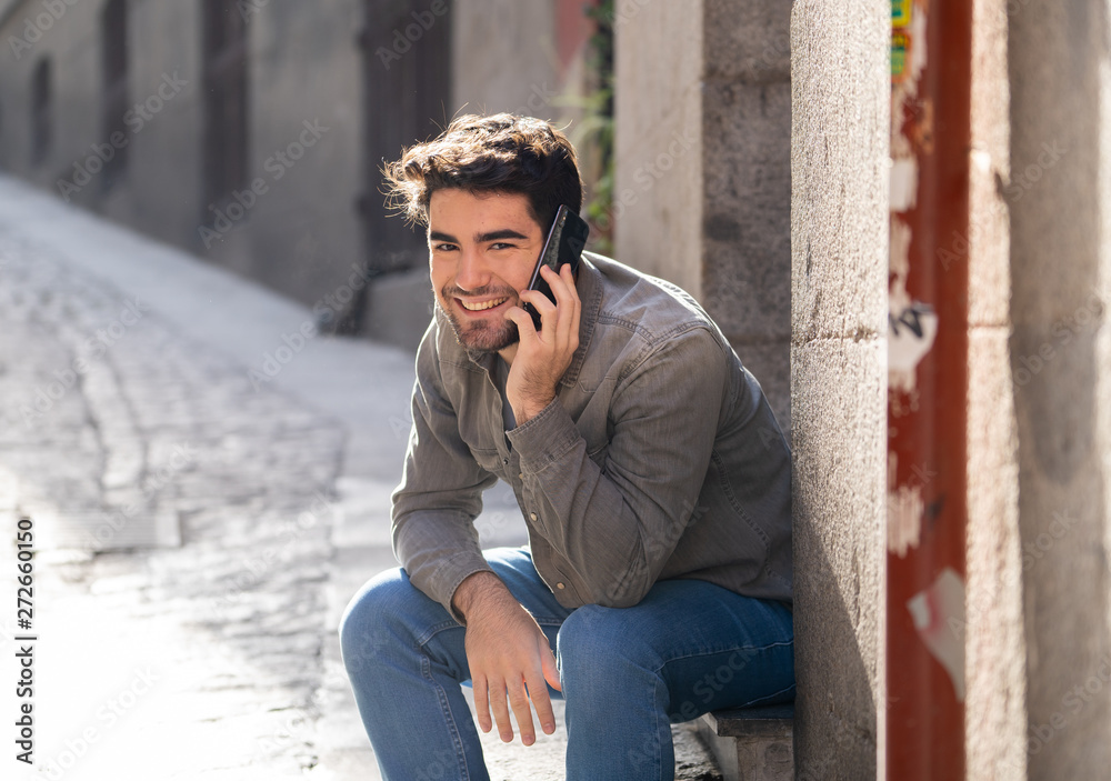 Young attractive happy man talking on smart phone in european city