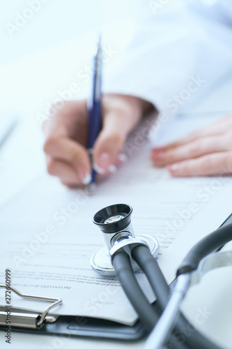Female medicine doctor hand holding silver pen writing something on clipboard closeup.. Ward round, patient visit check, medical calculation and statistics concept.