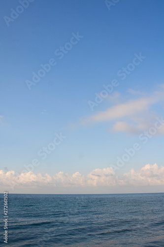 Dark blue sea and light blue sky with clouds