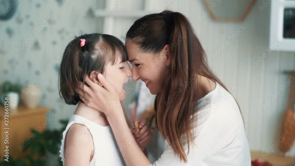 Close up, mother caresses daughter, girl gives mom to bite off bread, slow motion Close up, mother caresses daughter, girl gives mom to bite off bread, slow motion