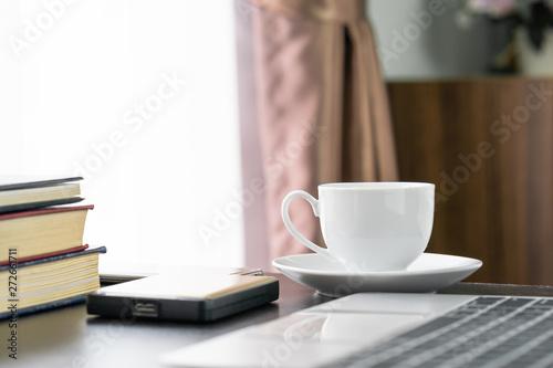 Coffee cup and laptop on table