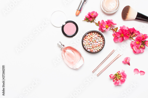 Different makeup cosmetic. Ball blush rouge face powder lipstick concealer bottle of perfume eyeshadow makeup brush spring pink flowers on light background top view flat lay. Beauty fashion background