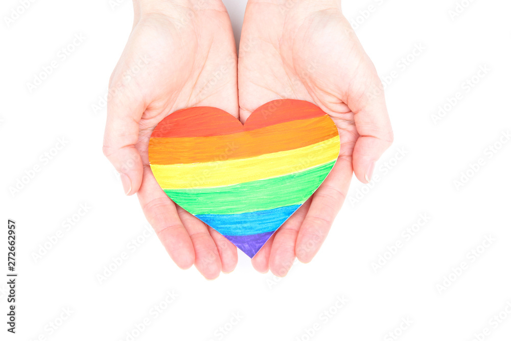 Female hands holding rainbow paper heart on white background Female hands holding rainbow paper heart on white background