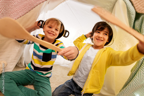 childhood and hygge concept - happy little boys with cooking pots playing in kids tent at home