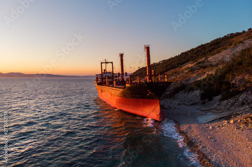 Aerial view of cargo ship run aground on wild coast, shipwreck after storm