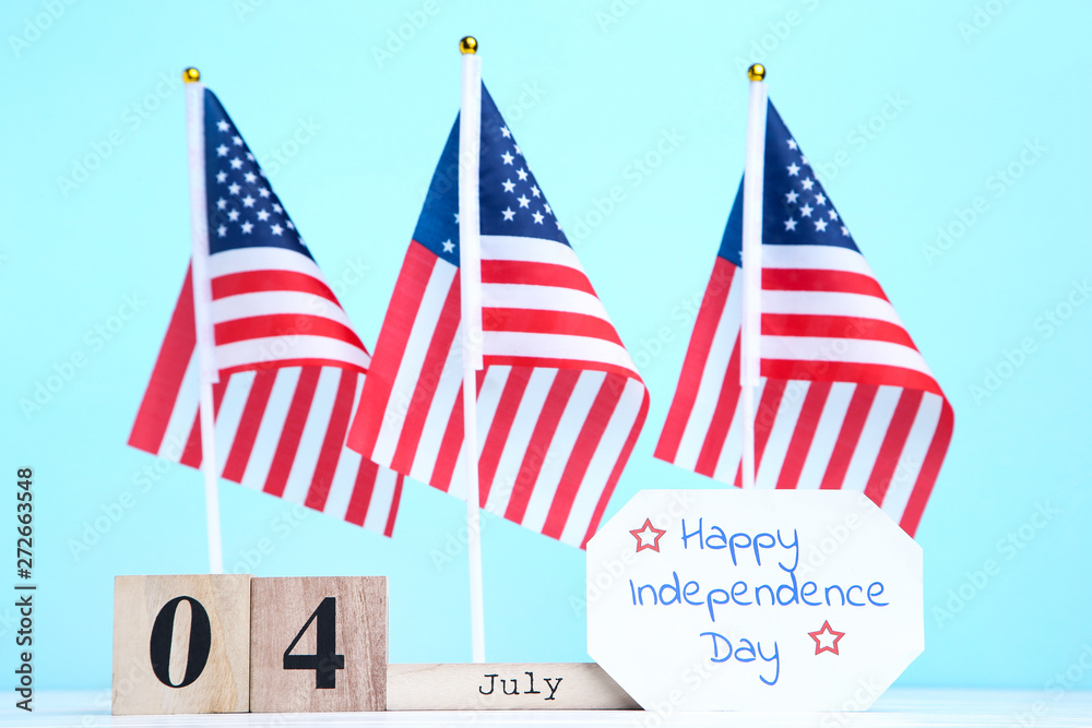 Obraz premium Text Happy Independence Day with american flags and cube calendar on blue background