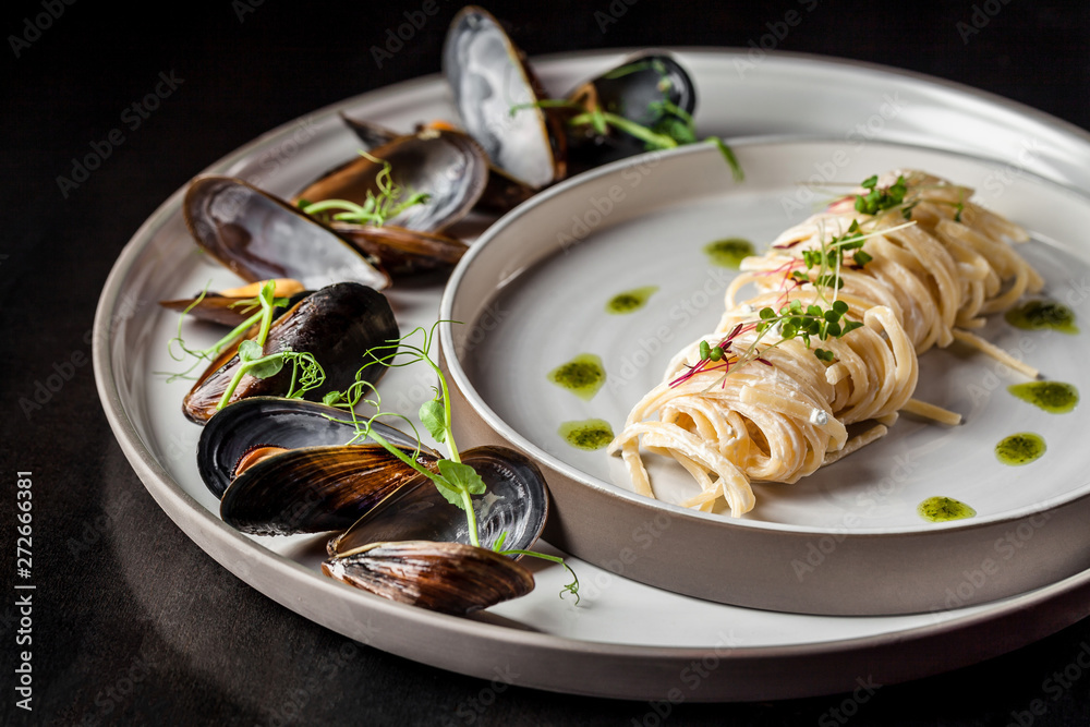 The concept of Italian cuisine. Pasta with cream sauce, pesto and seafood, mussels. European cuisine. Serving dishes in the restaurant with microgreen. copy space