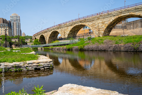 Cityscape scene of downtown Minneapolis, as seen from Mill Ruins Park. View of the Stone Arch bridge on sunny spring day © MelissaMN