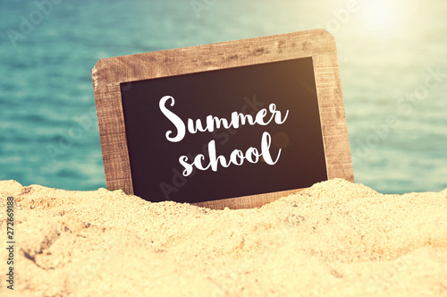 Summer school written on a vintage chalkboard in the sand of a beach, summer university concept photo
