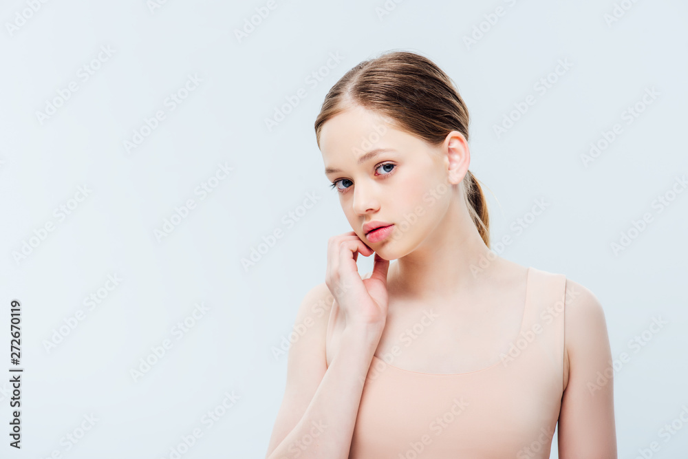 worried teenager looking at camera and touching face isolated on grey with copy space worried teenager looking at camera and touching face isolated on grey with copy space