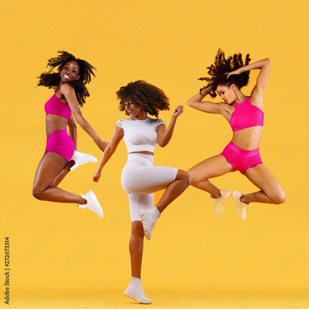 Three strong and happy athletic women, jumping or dancing on