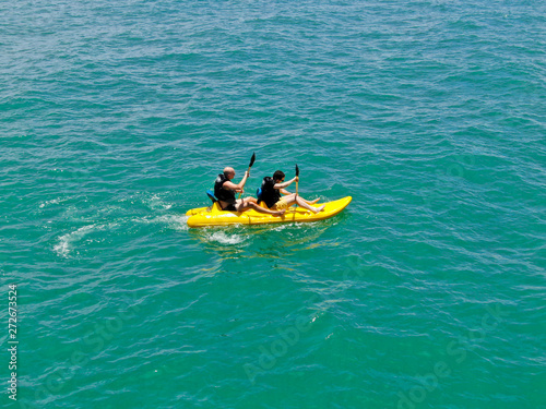 Aerial view of strong young active men kayaking on the clear blue turquoise water of the ocean. Active vacation. Praia do Forte, Brazil