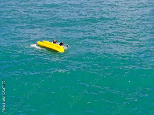 Aerial view of strong young active men capsizing with their kayak on the clear blue turquoise water of the ocean. Active vacation. Praia do Forte, Brazil. 