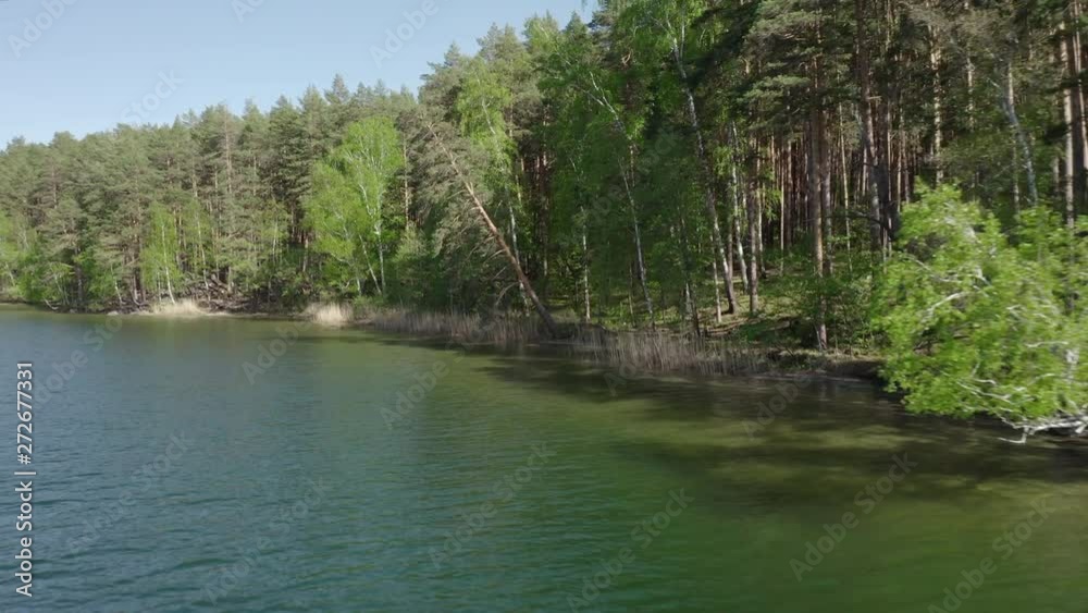 Lake with turquoise water, green trees; montain in the background; reflection in the water; beautiful summer landscape lake surrounded by forest; aerial drone shot over beautiful mountain forest lake